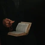 padre con rosario en mano y una biblia