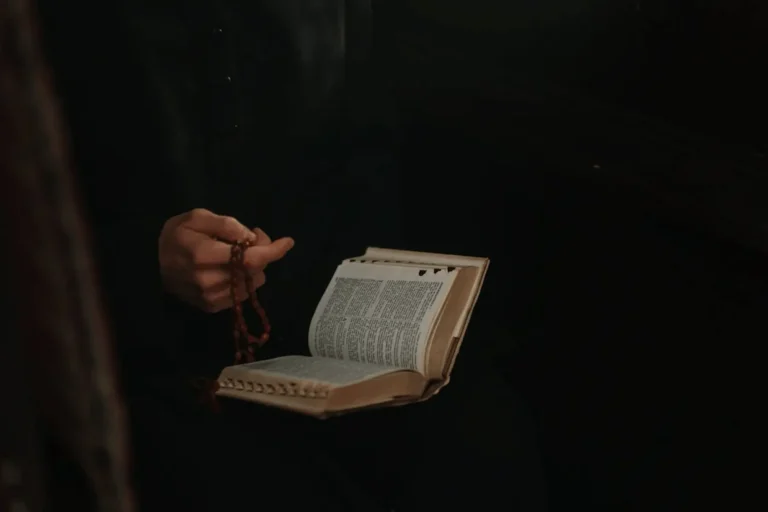 padre con rosario en mano y una biblia