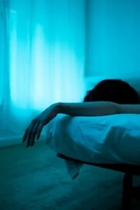 una mujer acostada boca abajo al borde de la cama