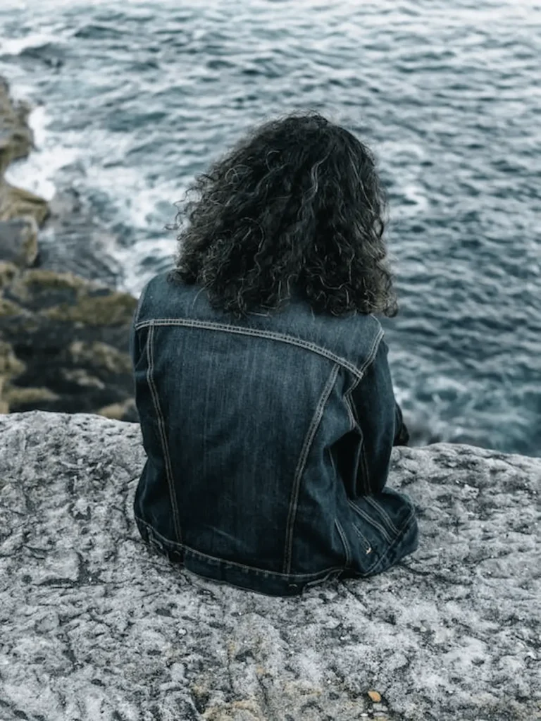 una mujer sentada al borde mirando hacia el mar