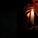 una vela iluminando la boca de alguien en un cuarto oscuro